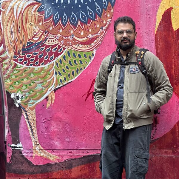 Anuj Deshpande standing in front of a colourful mural